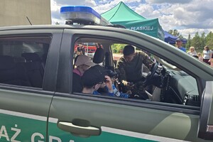 Dzień Dziecka z funkcjonariuszami funkcjonariusz pokazuje dzieciom samochód służbowy