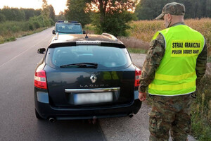 Zatrzymanie kuriera Funkcjonariusz Straży Granicznej stoi tyłem, przed nim pojazd marki Renault.