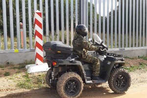 Patrol SG na quadzie Funkcjonariusz Straży Granicznej na quadzie. Za nim płot i słup graniczny polski. Po drugiej stronie płotu widoczny słup graniczny białoruski.