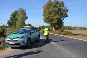 Kontrola ruchu drogowego Funkcjonariusz SG stojąc na drodze przy służbowym samochodzie tarczką stop daje sygnał do zatrzymania się