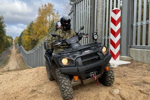 Patrol SG na quadzie Patrol Straży Granicznej na quadzie. w Tle bariera fizyczna oraz słup graniczny Polski.