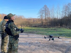 Funkcjonariusze SG Dwaj funkcjonariusze SG stojący na przeciw lasu, którzy obsługują bezzałogowy statek powietrzny