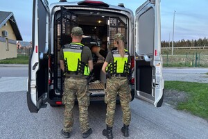 Zatrzymani nielegalni migranci Zatrzymani nielegalni migranci siedzący w samochodzie SG, na pierwszym planie dwóch funkcjonariuszy SG