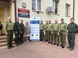 Drugie spotkanie Grupa osób stoi obok siebie na tle budynku. Po środku między nimi ustawiony jest baner.