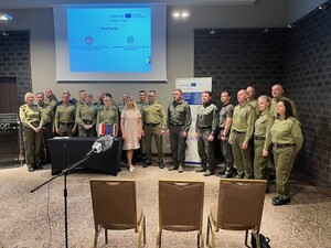 Zdjęcie grupowe Grupa osób stojących obok siebie w sali konferencyjnej. Po środku między nimi ustawiony jest baner projektu.