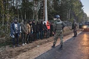 Zatrzymani migranci Zatrzymani migranci stojący na pasie drogi granicznej