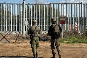 Funkcjonariusz Straży granicznej i Wojska Funkcjonariusz Straży granicznej i Wojska na tle płotu granicznego.