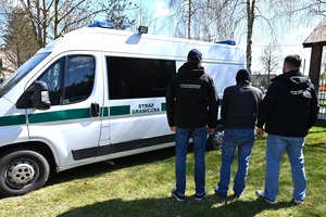 Z Litwy do Polski poza prawem Trzech mężczyzn stoi odwróconych tyłem przy samochodzie.