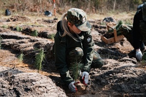 Sadzenie lasu ze Strażą Graniczną Funkcjonariuszka Straży Granicznej sadzi drzewo.